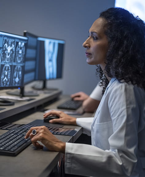 female researcher reviewing brain scans on a desktop computer