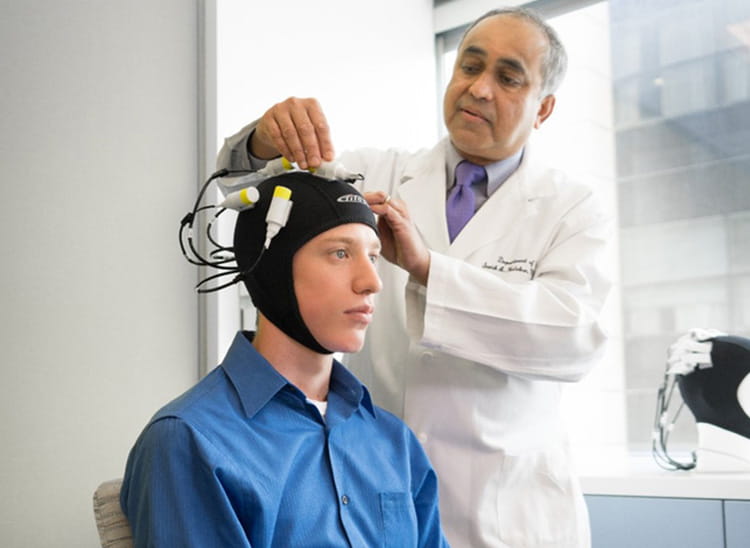 Doctor using a magnetic brain stimulation cap on patient