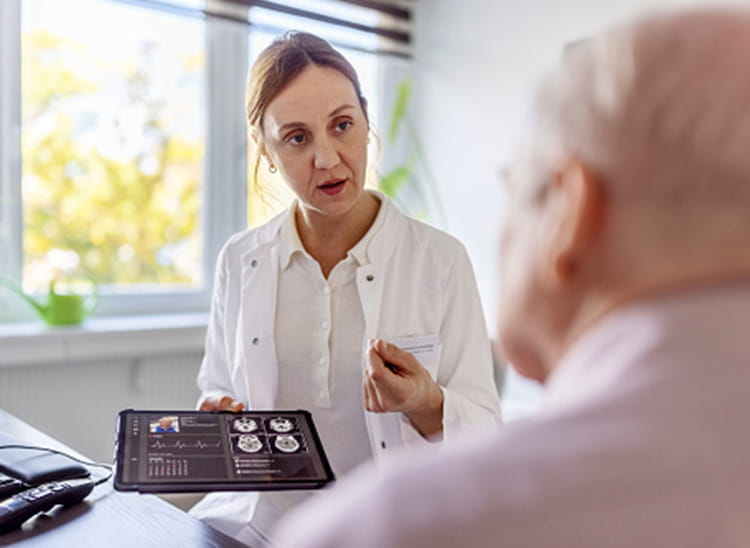 doctor holding Ipad with scan imagery and speaking to patient